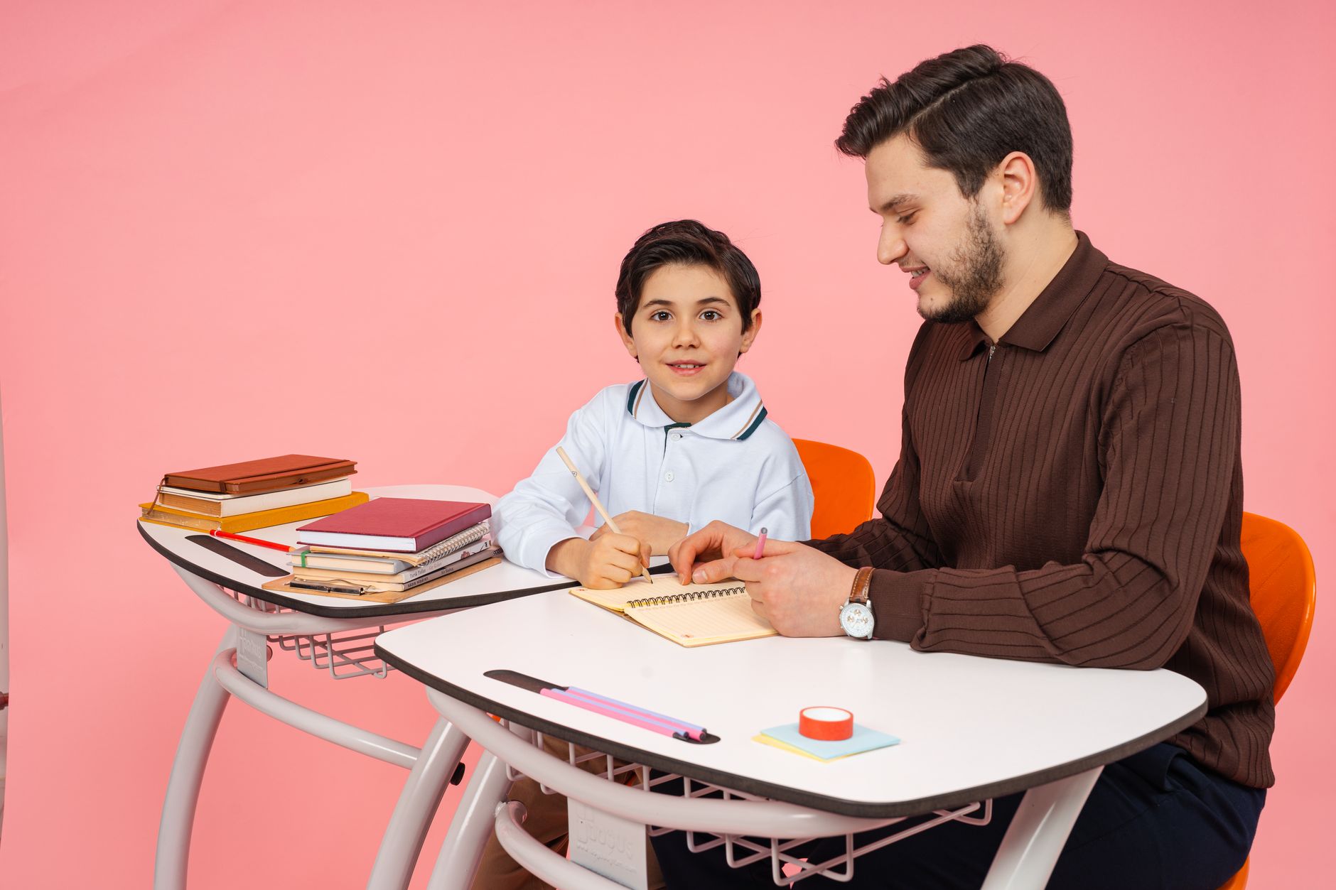A father assists his young son with homework at a desk in Yalova, Türkiye.