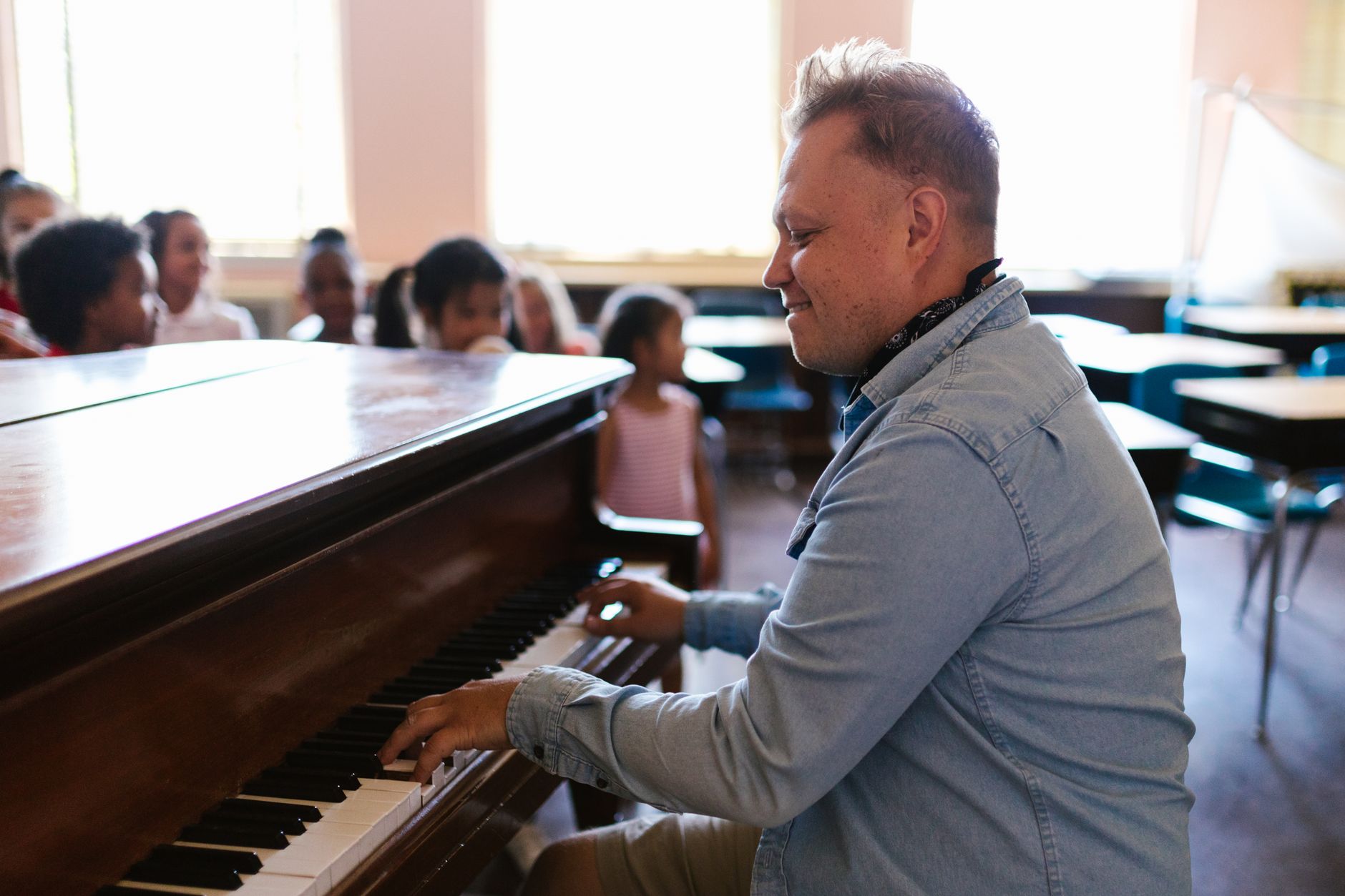 Music teacher engages students with lively piano performance in classroom setting.