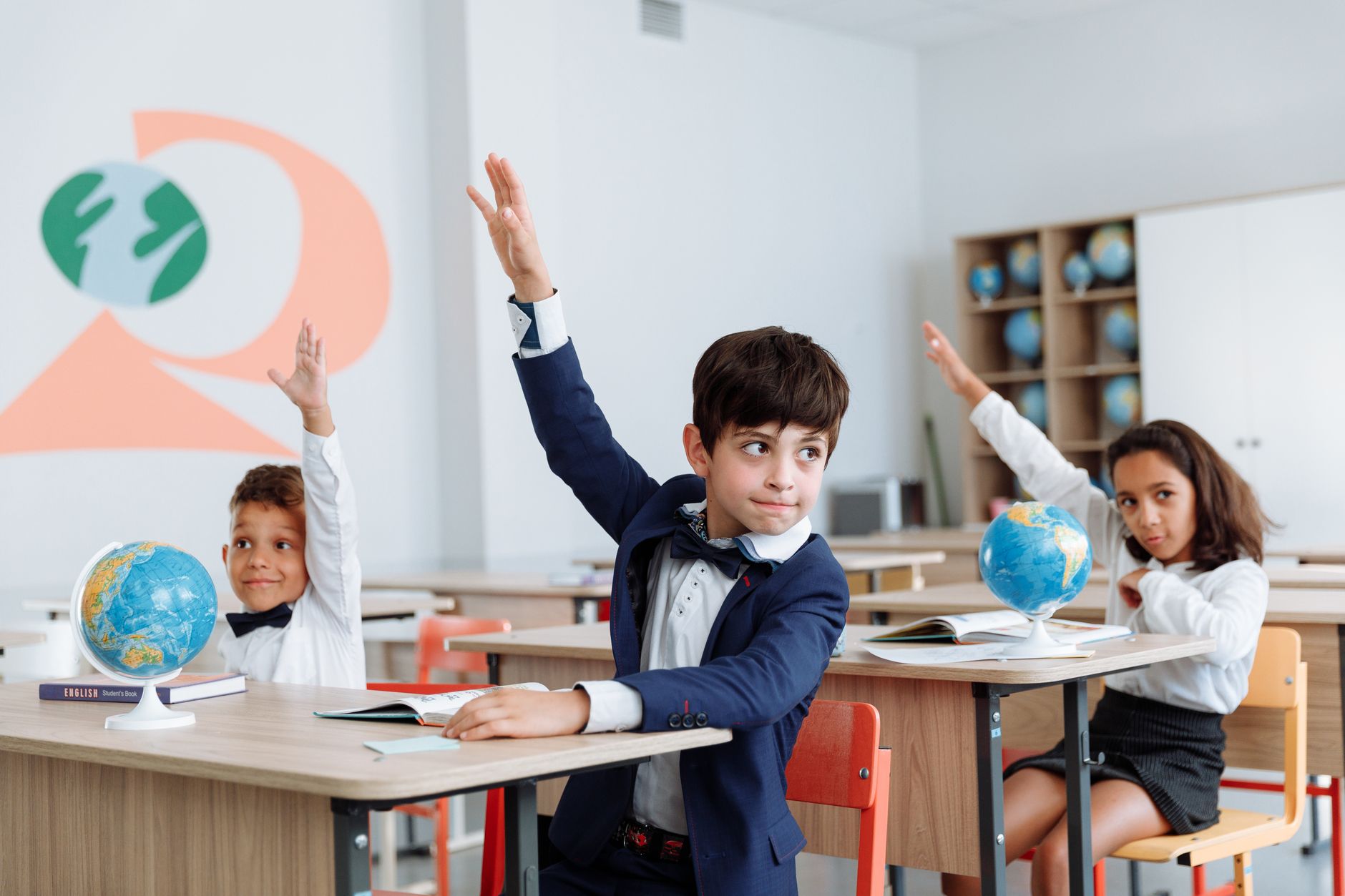 Students in a classroom eagerly raising their hands during a lesson.